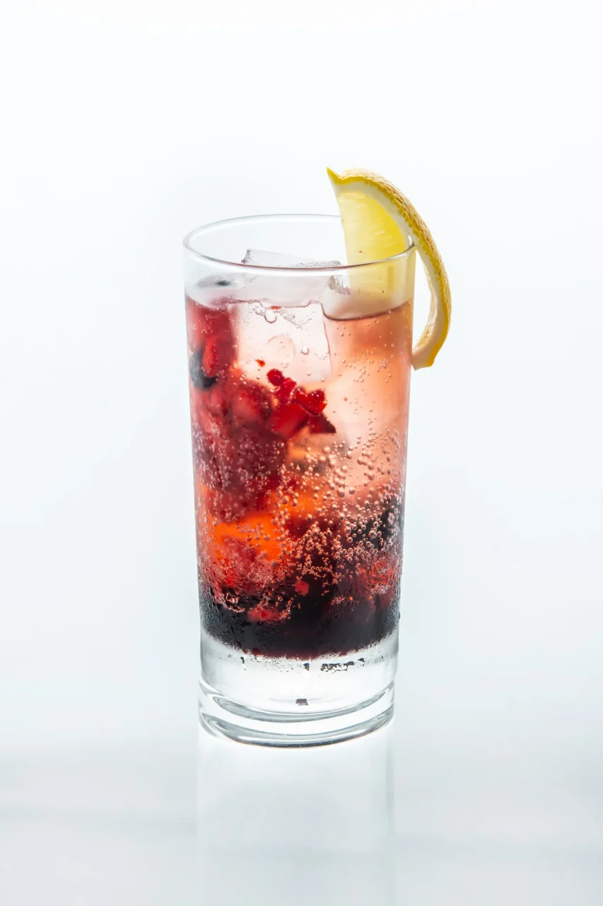 カシスジンジャー（ノンアルコール）のグラス。ルビー色の液体に氷とレモン輪が添えられている。