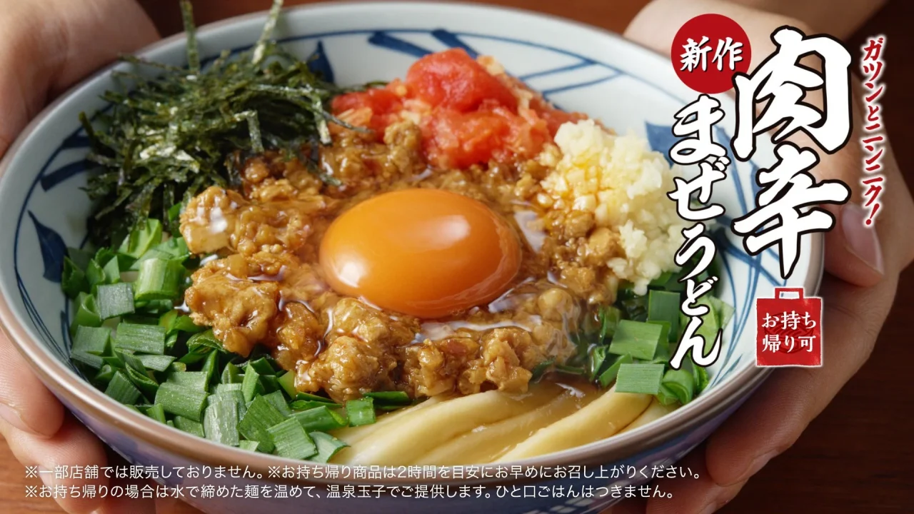 肉辛まぜうどんの丼。玉子、特製ミンチ、刻みニラ、生ニンニク、ガリトマト、刻みのりが盛り付けられている。
