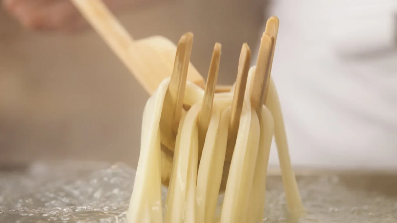 丸亀製麺の店内で、麺職人が釜からうどんをすくい上げる様子