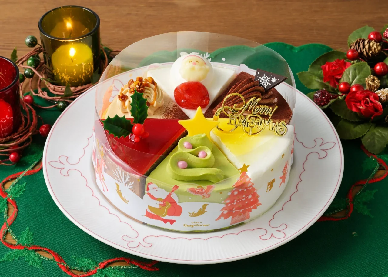 6つのクリスマスアソートのケーキ。透明ドーム付きで、サンタやツリーのイラストが描かれた皿に盛られています。