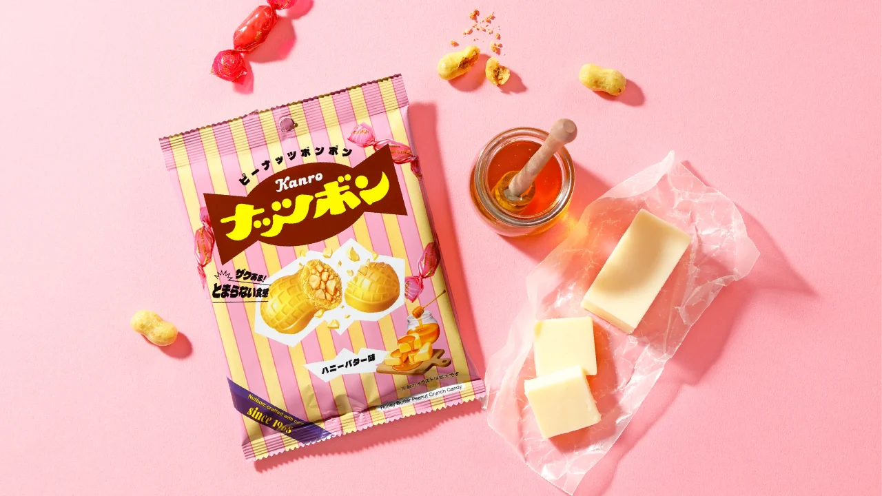 ナッツボンハニーバター味の袋と飴を並べたピンク背景の写真