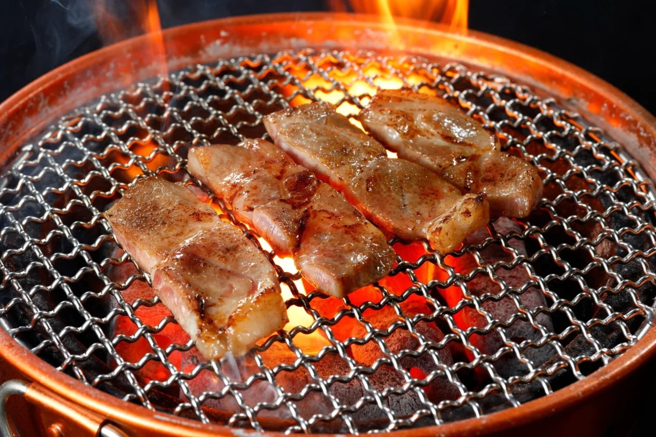七輪の網で焼かれる肉厚ロースステーキ