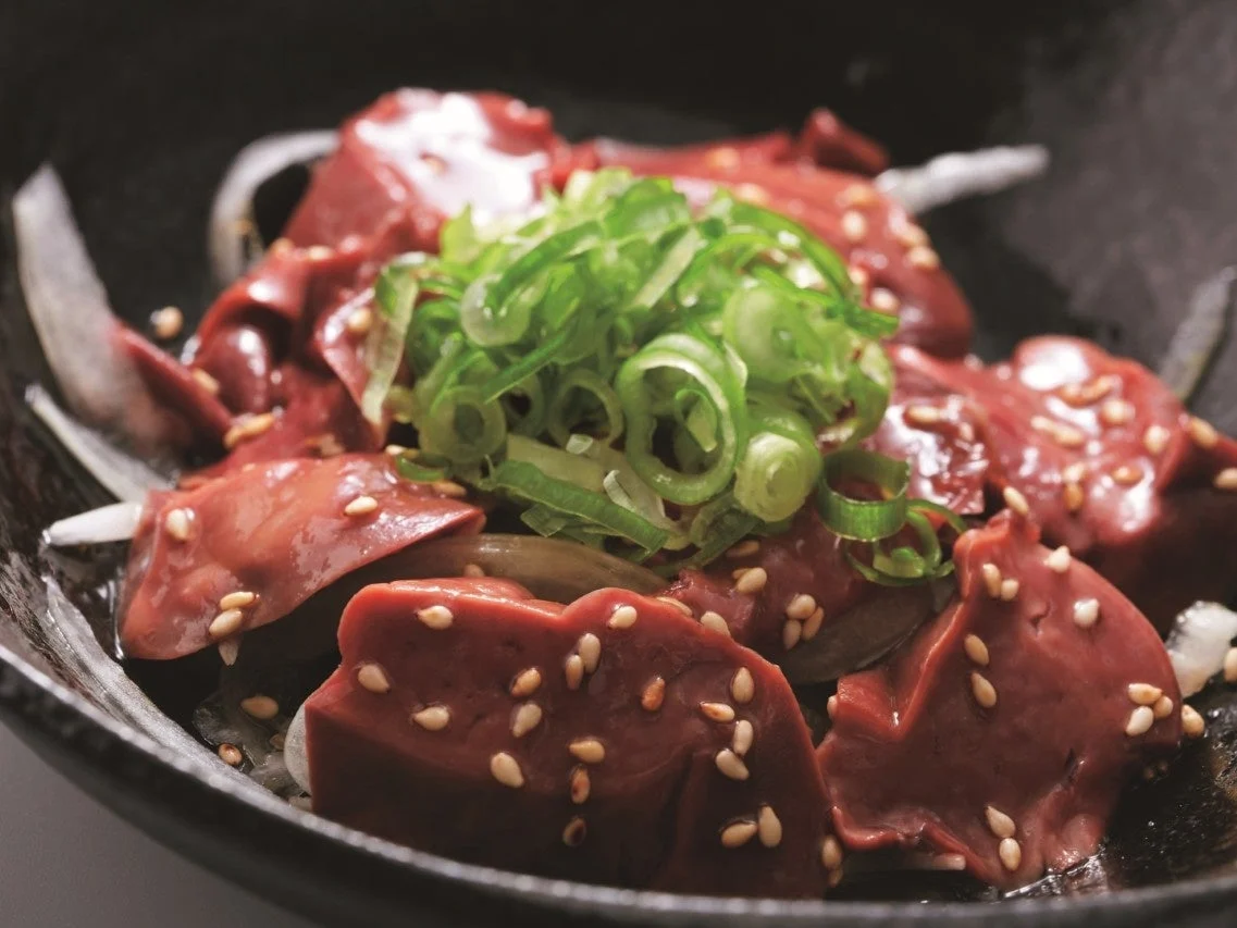 鶏のレバ刺し～一番絞りごま油～（きも刺し）。黒い器に盛られ、刻んだ青ねぎとごまが載る