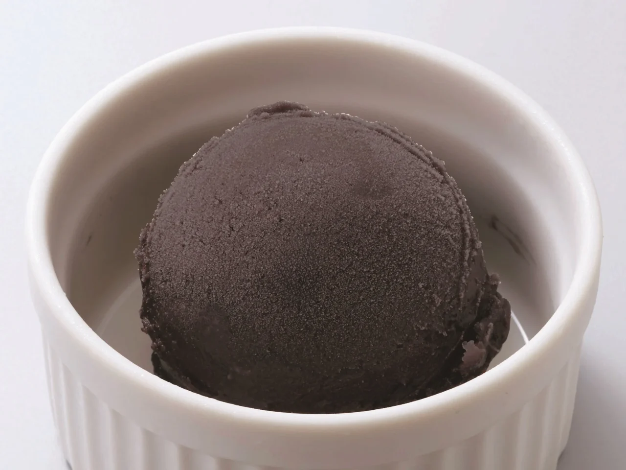 白い器に盛られた黒い一玉の竹炭ジェラート