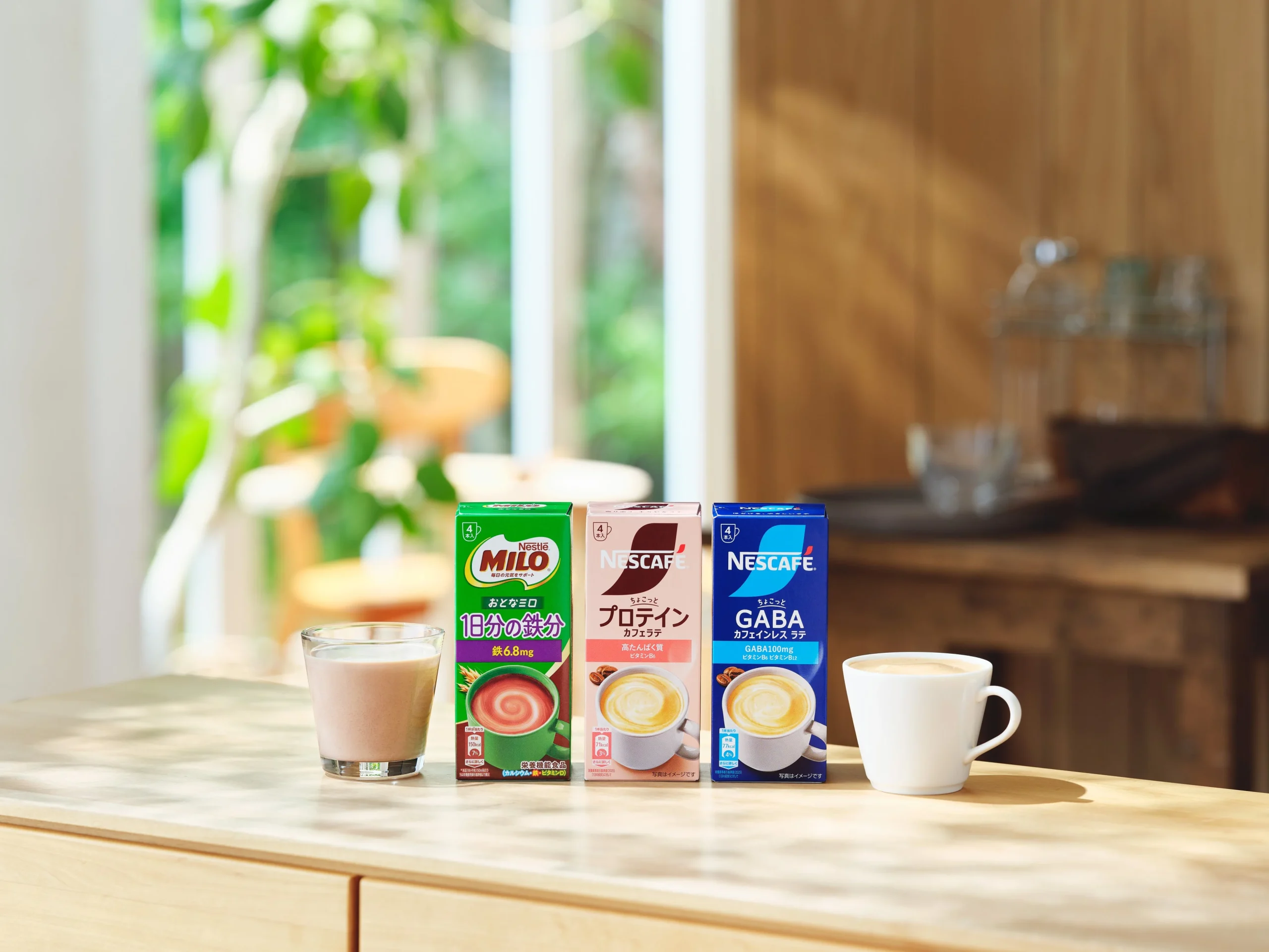 ネスレ「大人の健康計画」シリーズの3製品と飲み物を入れたグラス、白いカップ