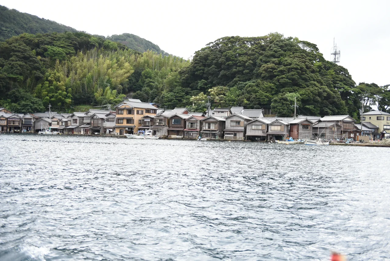 伊根の舟屋が湾岸に並び、手前に水面が広がる
