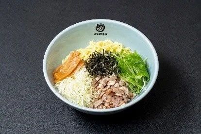 壱角家 油そば総本店の油そば。黒い器に麺とトッピングが盛り付けられている。