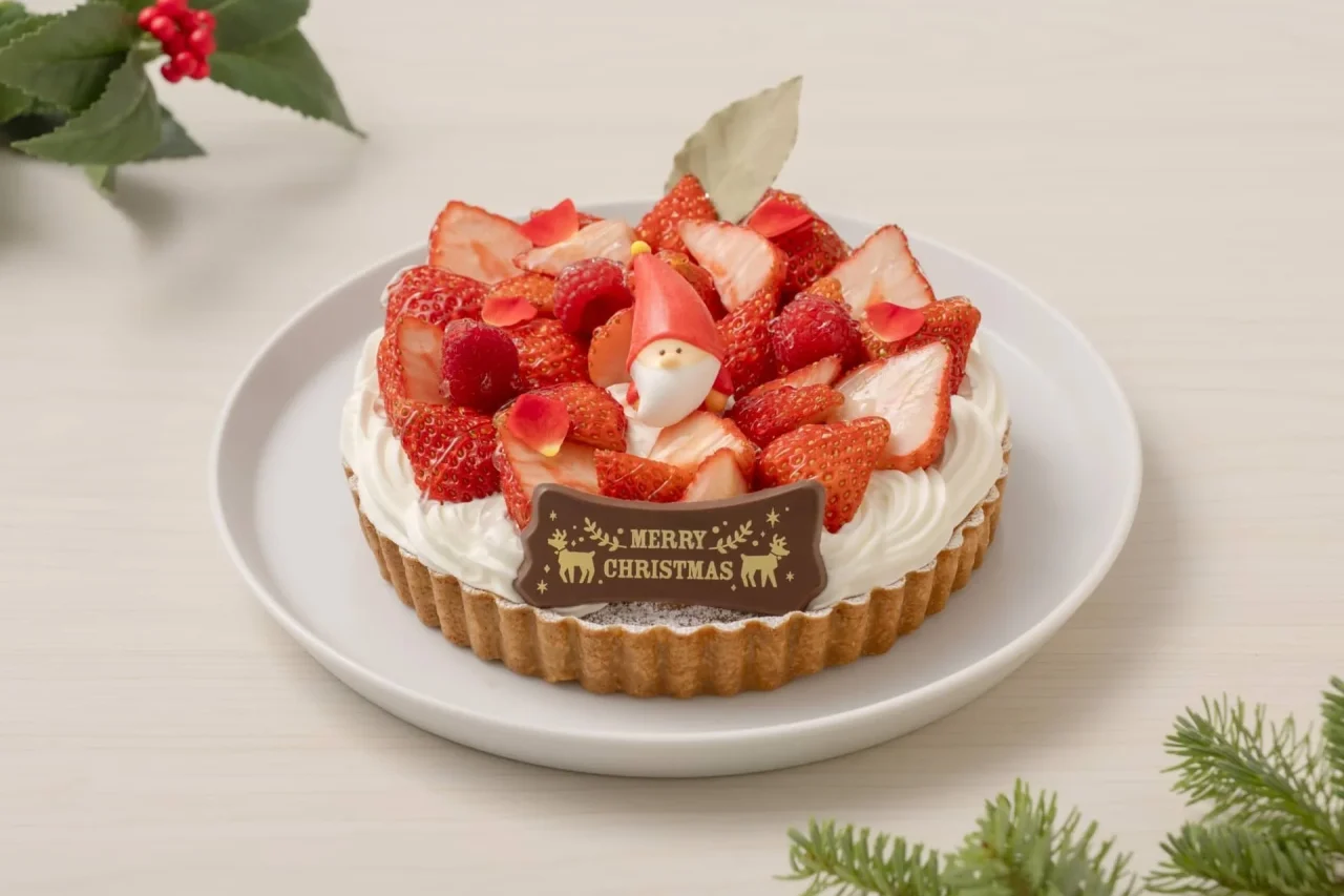 クリスマス 苺のタルト。苺とラズベリーを盛り付け、サンタクロースの飾りとMERRY CHRISTMASのプレートが添えられたタルト。