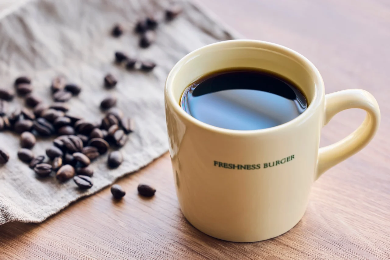 フレッシュネスバーガーのロゴ入りマグカップに入ったドリップコーヒーとコーヒー豆