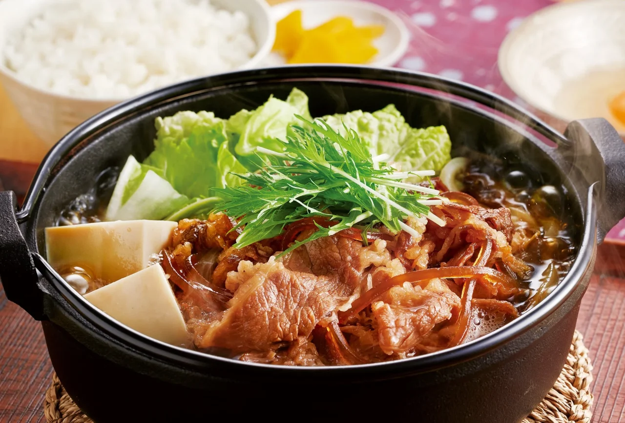 肉増し!すき焼き鍋定食。黒い鍋に牛肉・豆腐・野菜を煮込んだ鍋料理とご飯。