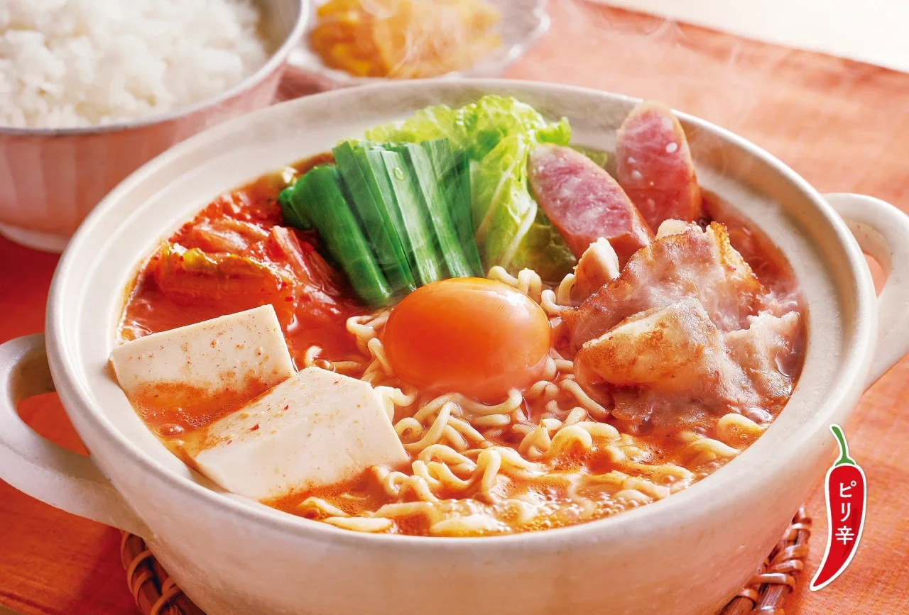 旨辛スープのキムチチゲ定食。赤いスープに麺、卵、豆腐、肉、ネギが入った鍋料理。