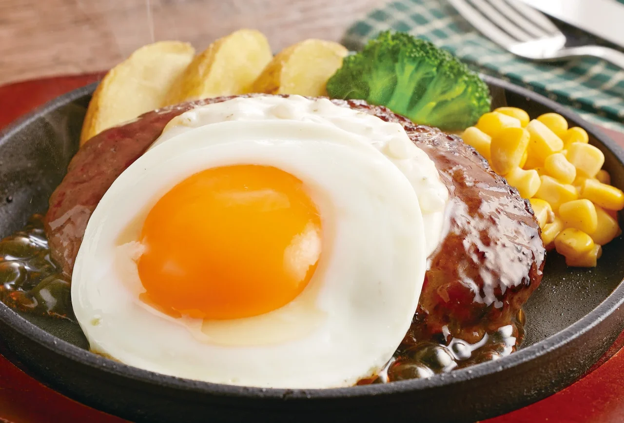 てりたまハンバーグ。鉄板にハンバーグと目玉焼き、タルタルソース、付け合わせを盛り付けた外観。
