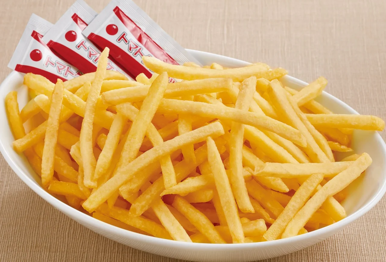 メガ盛りポテトフライ。白い皿に山盛りのポテトフライとソースのパックが添えられている。