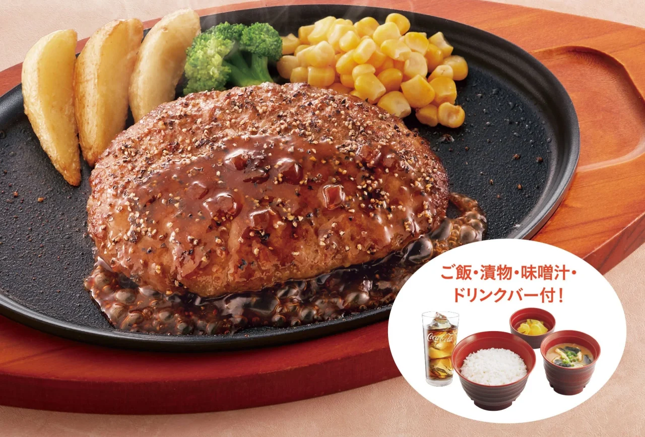 ペッパーハンバーグ。黒い鉄板にソースをかけたハンバーグとポテト、ブロッコリー、コーンを盛り付けた定食。