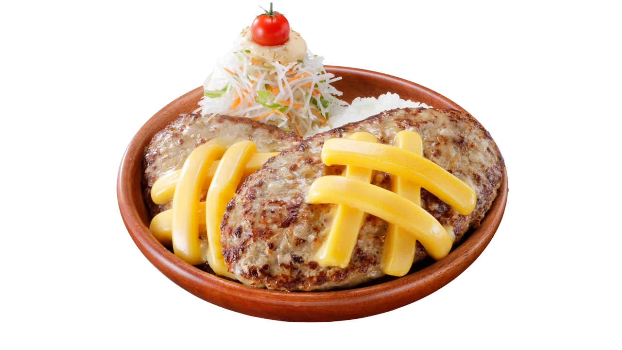 黄色い棒状のトッピングを載せたハンバーグ2枚と、ライス、山盛りのサラダを盛った皿