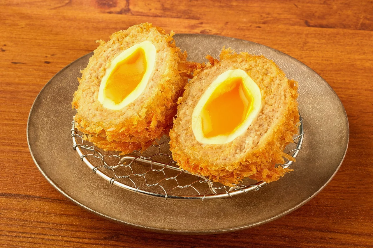 半熟玉子の断面が見える丸いかつを二つ並べた皿