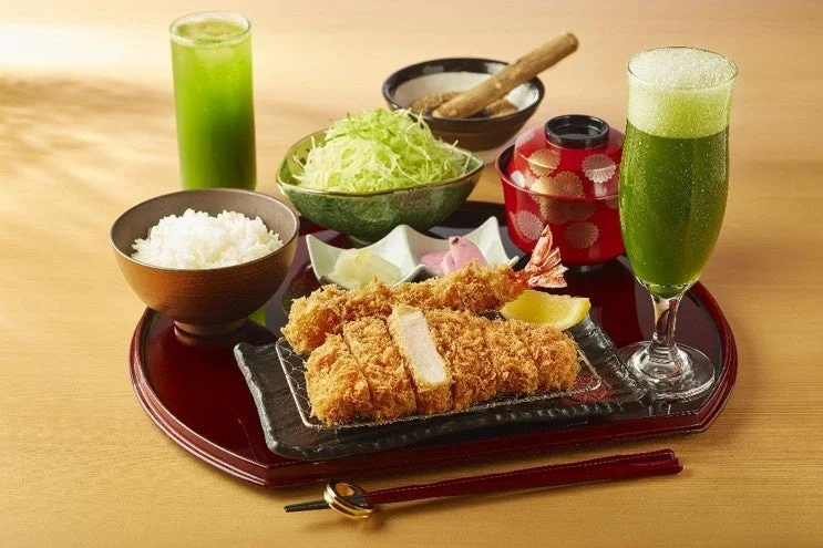 とんかつの食事に緑色のドリンク2杯を添えた卓上風景