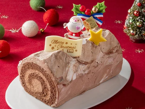 Xmasブッシュ・ド・ノエル。サンタ飾りとMerry Christmasプレートを載せた丸太型ケーキ