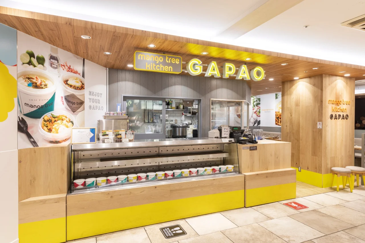 マンゴツリーキッチンのGAPAO店舗外観。木目の壁と黄色い看板が並ぶ