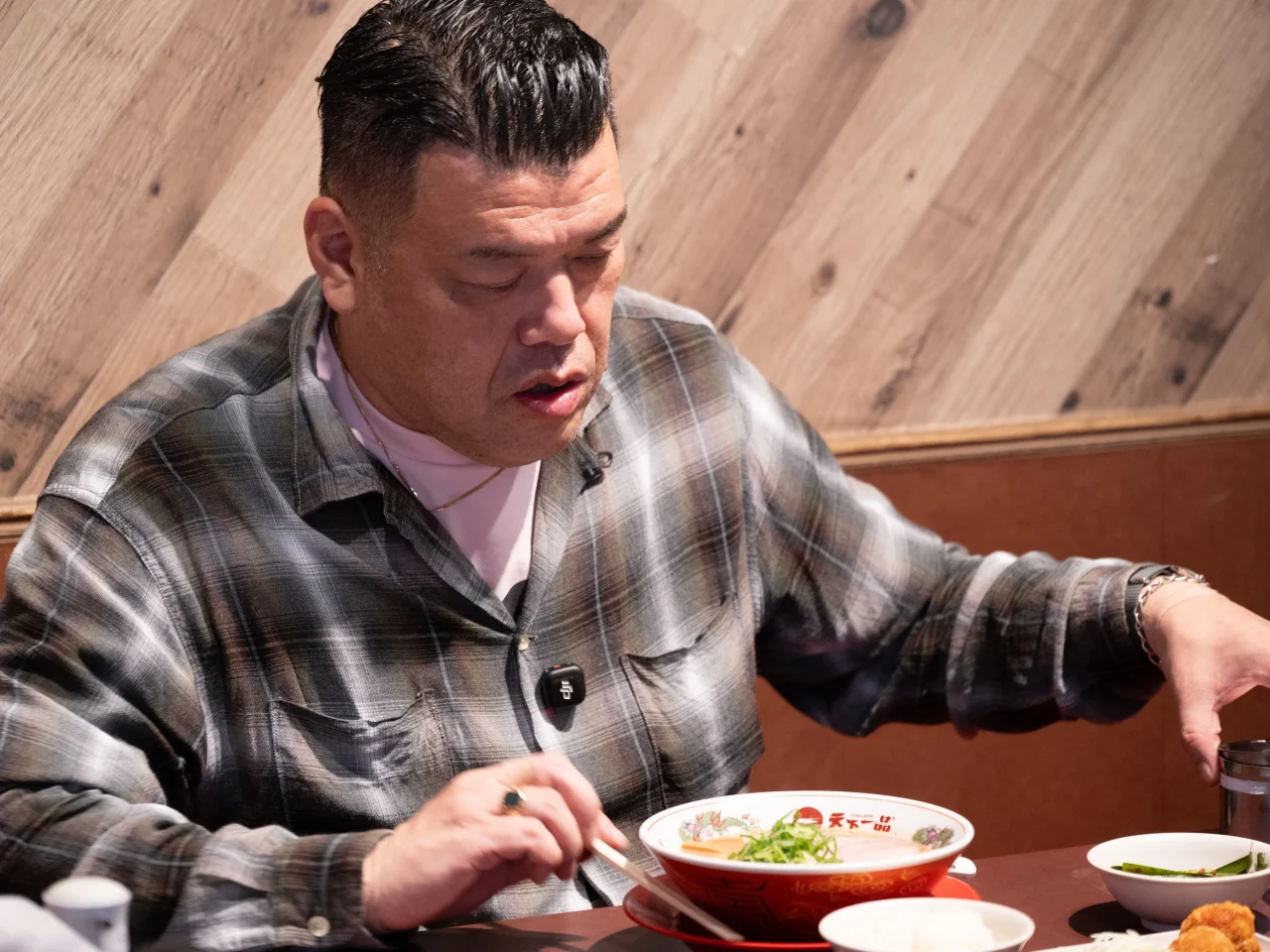 いつものこってりラーメンを召し上がり中の、チェックシャツの男性