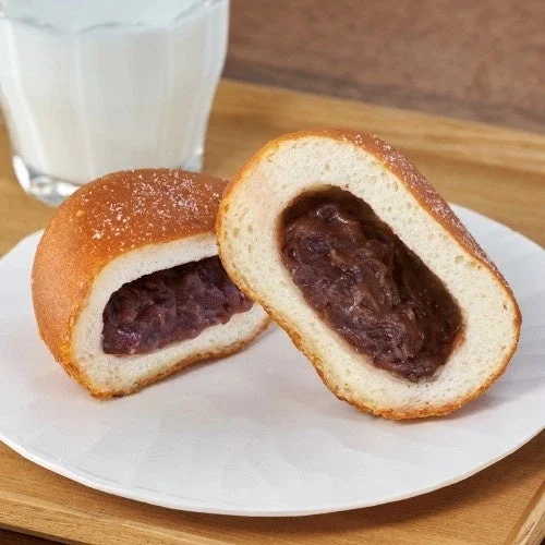 半分に割ったあん入りの丸いパンと牛乳のグラス
