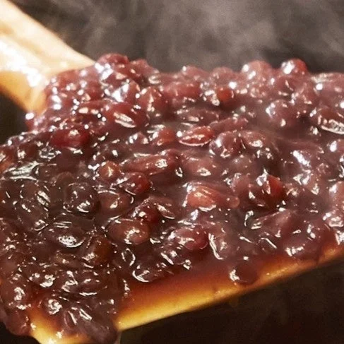 木べらにのった湯気の立つ自家製粒あん