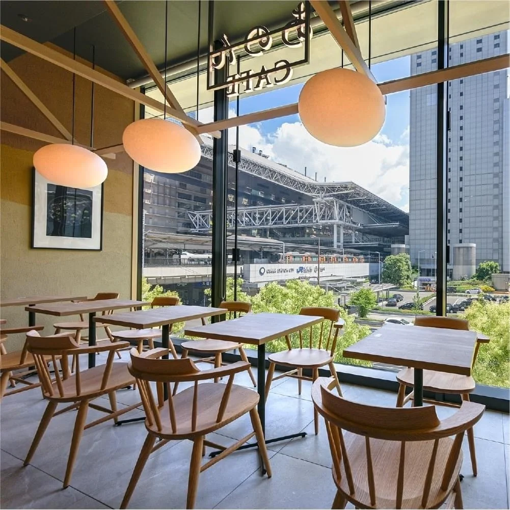 KYOTO あのん CAFEの店内。木製のテーブルと椅子、丸い照明、大きな窓