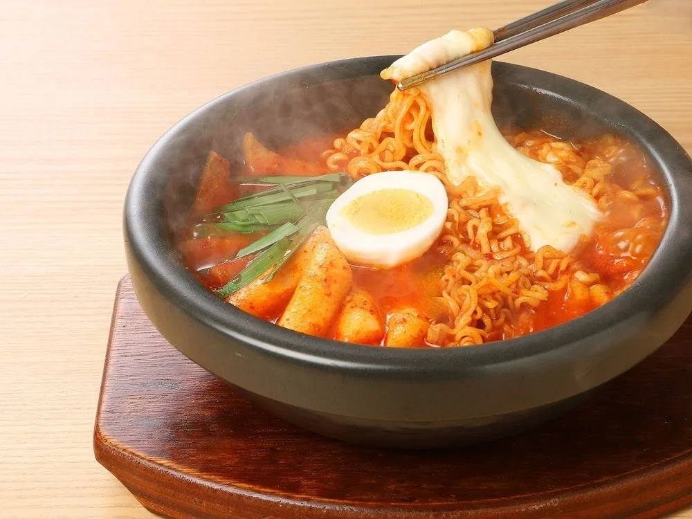 チーズラッポギ。石鍋に入った辛いスープに麺と餅、ゆで卵、伸びるチーズ