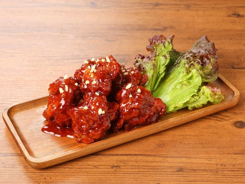 木製プレートに盛られたフライドチキン(ヤンニョム)とサンチュ