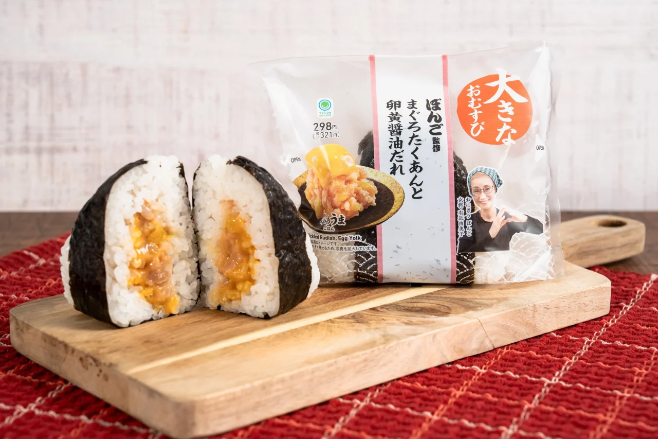 大きなおむすび まぐろたくあんと卵黄醤油だれのパッケージと、断面を見せたおむすび