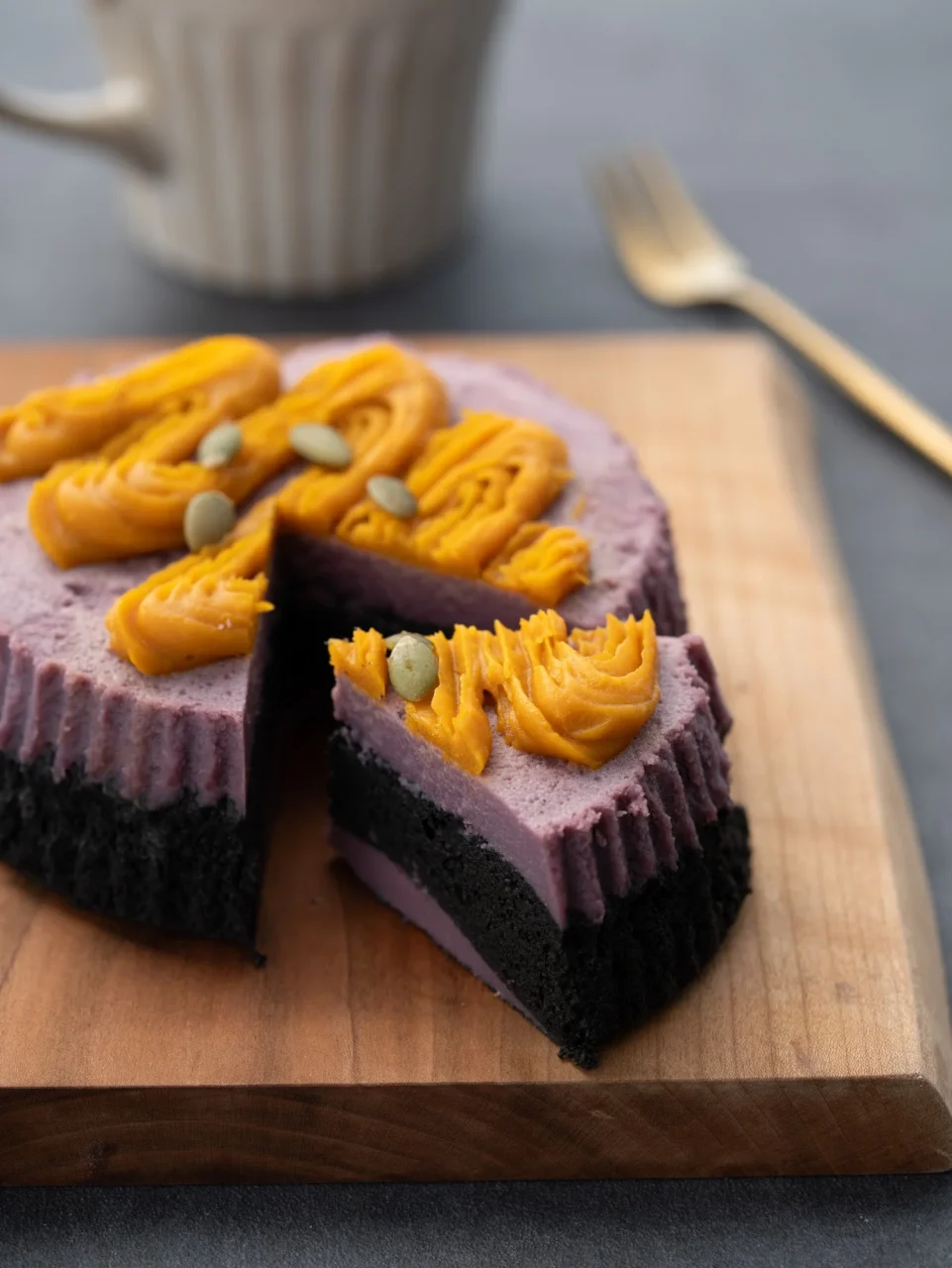 ブラックマドレーヌと紫芋のチーズケーキ。黒い生地に紫芋、かぼちゃ色のクリーム