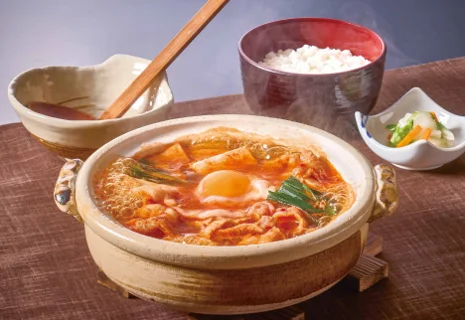 黒豚チゲうどん鍋ごはん付。土鍋の赤いスープに卵とねぎ、ごはんと小鉢