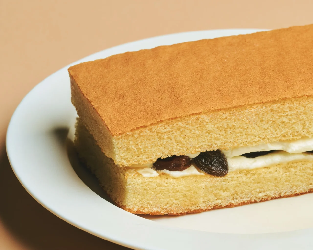 白い皿にのったふあふあレーズンサンド。クリームとレーズンをはさんだ断面