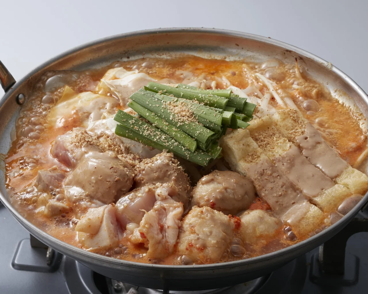 焙煎胡麻から鍋。ニラやつくね、鶏肉、厚揚げが入った赤いスープの鍋