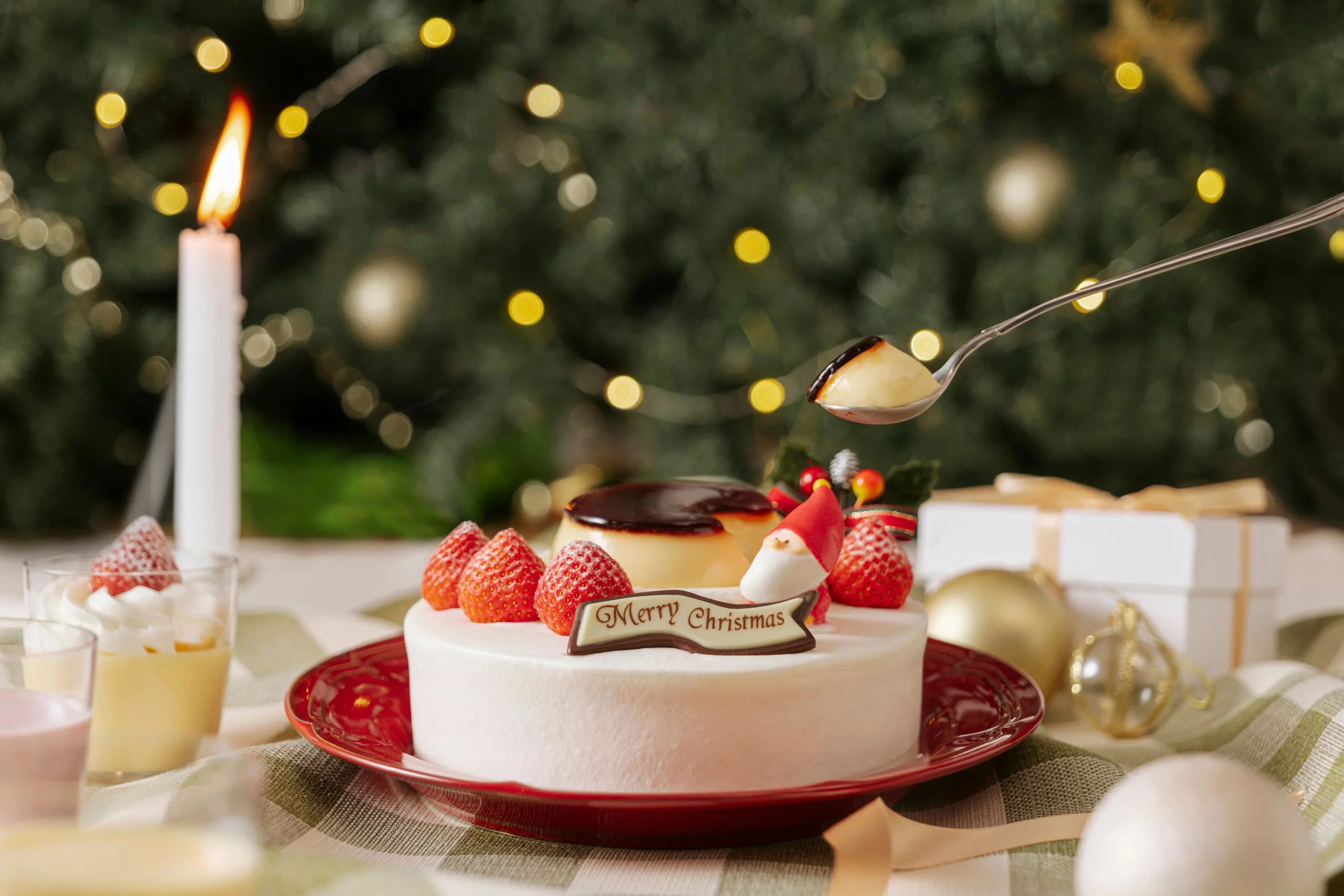 プリンをのせた白いホールケーキとスプーンですくったプリン、クリスマス飾り