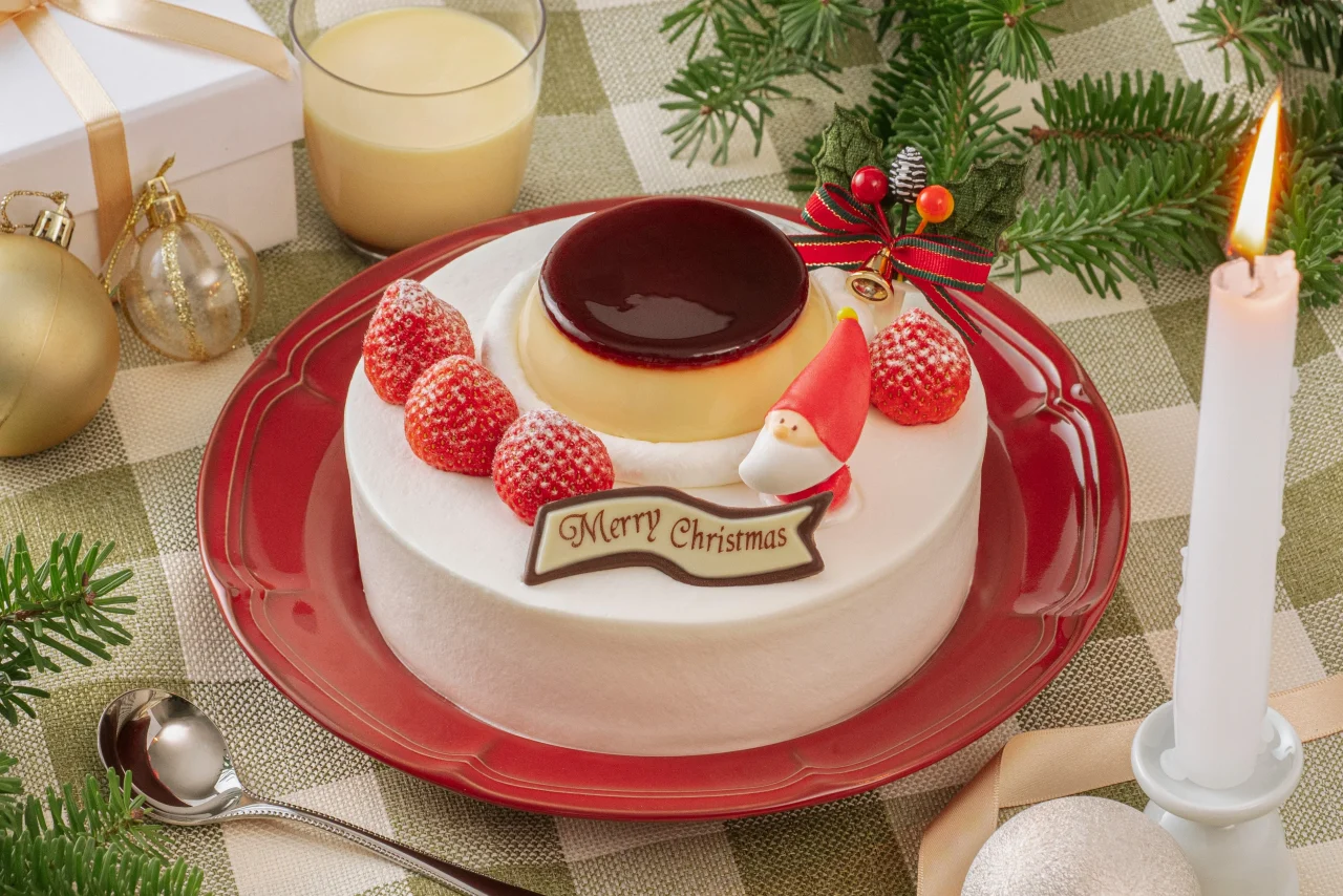 クリスマス プリンケーキ。白いケーキに大きなプリンと苺、サンタを飾った様子