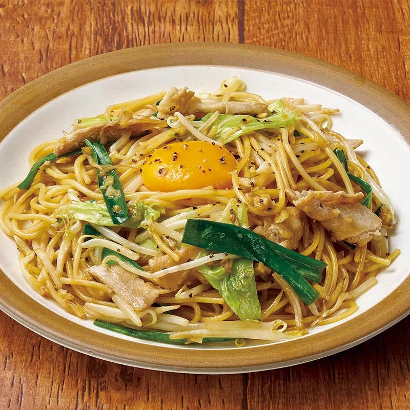 背徳!にんにくパスタ。卵黄とネギ、野菜、肉がのった麺の皿