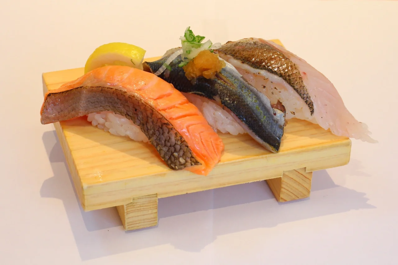 木の台に載った秋の炙り三昧の握り寿司3貫とレモン