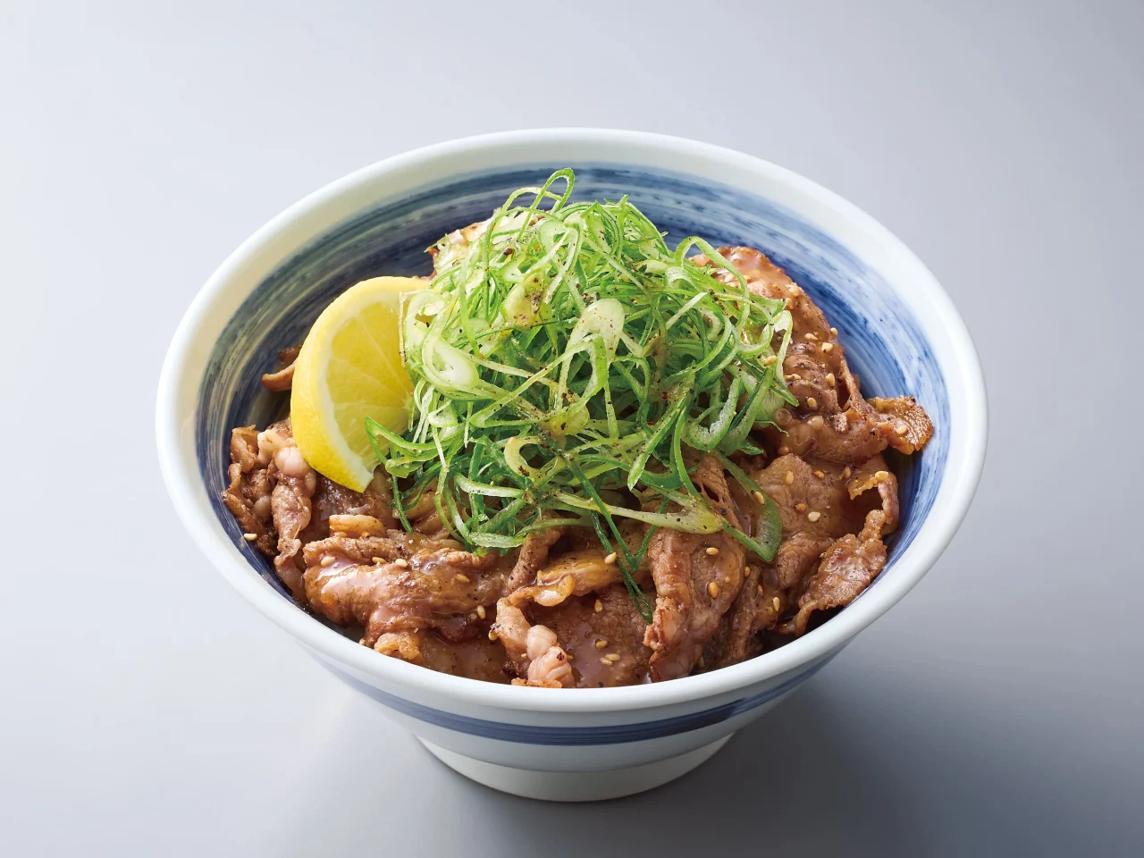 京都産九条ねぎ旨塩牛カルビ丼。青い縁の丼にカルビとねぎ、レモン