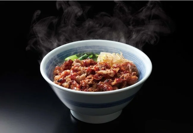 湯気の立つ焼きたてのカルビ丼。青い縞の丼に焼いたカルビが盛られている