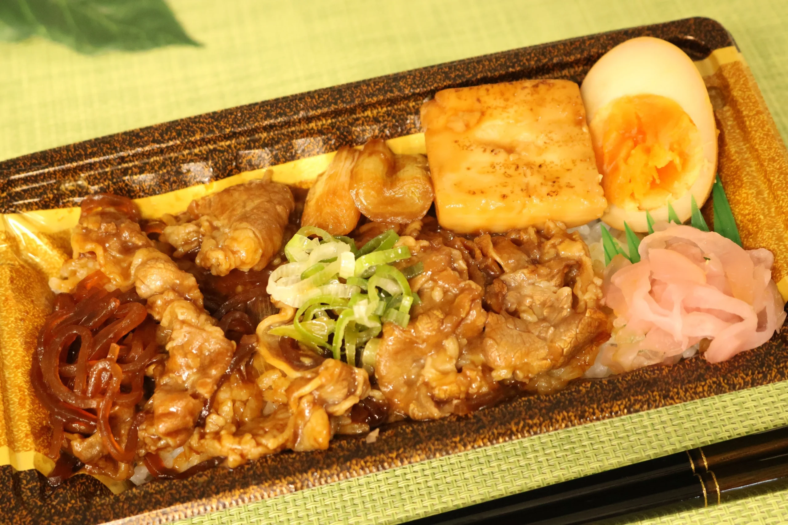 牛すき焼き重。牛バラ肉、焼き豆腐、煮卵、ねぎ、紅生姜が入った容器