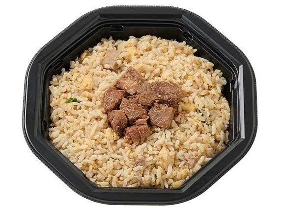 黒い容器に入った、肉をのせたチャーハン