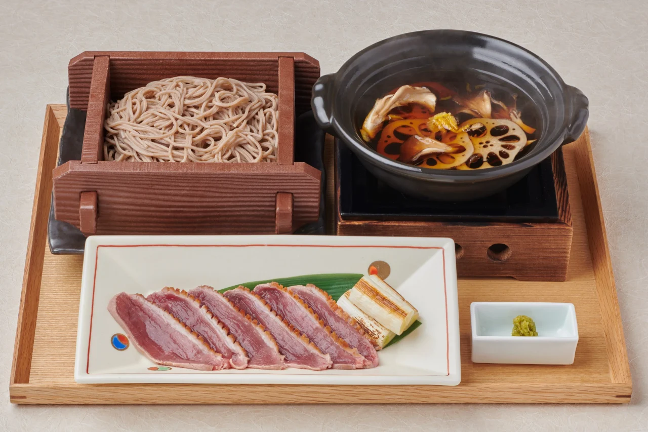 京鴨のつけ蕎麦。せいろの蕎麦、鴨ロースの皿、具入りの鍋、薬味