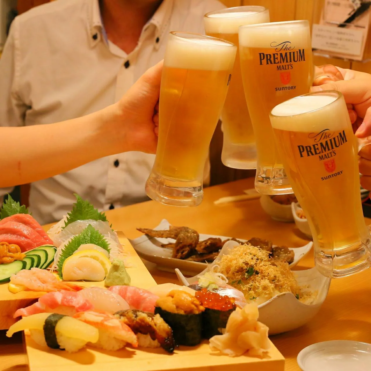 や台ずし宴会イメージ。ビールのジョッキで乾杯し、寿司や料理が並ぶ卓