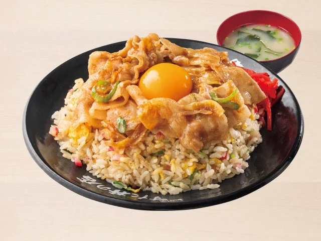 すたみなチャーハン。豚肉と卵黄をのせた黒い皿のチャーハンと味噌汁