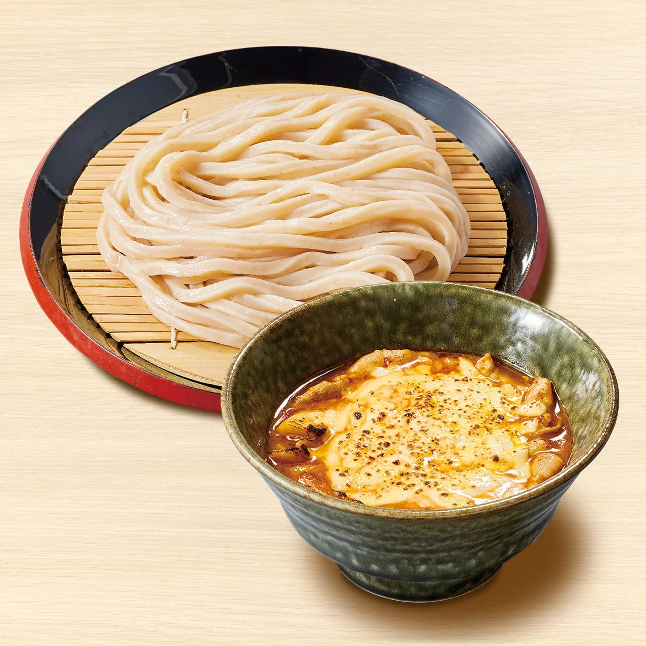 炙りチーズ旨辛肉つけ汁うどん。ざる盛りの麺と、チーズをのせたつけ汁