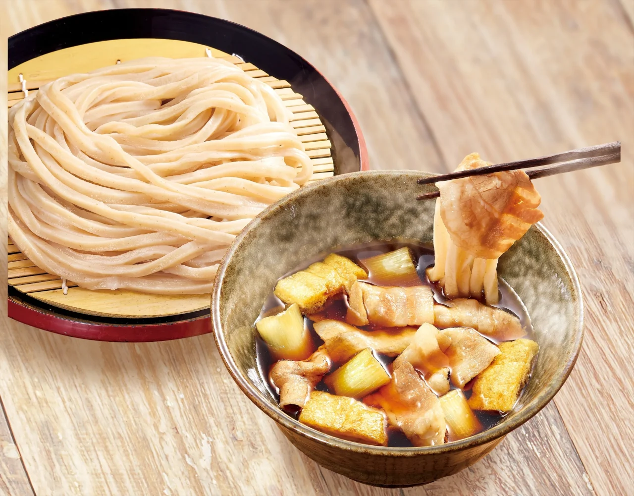 ざるにのった武蔵野うどんと、豚肉と揚げなすの入ったつけ汁の器
