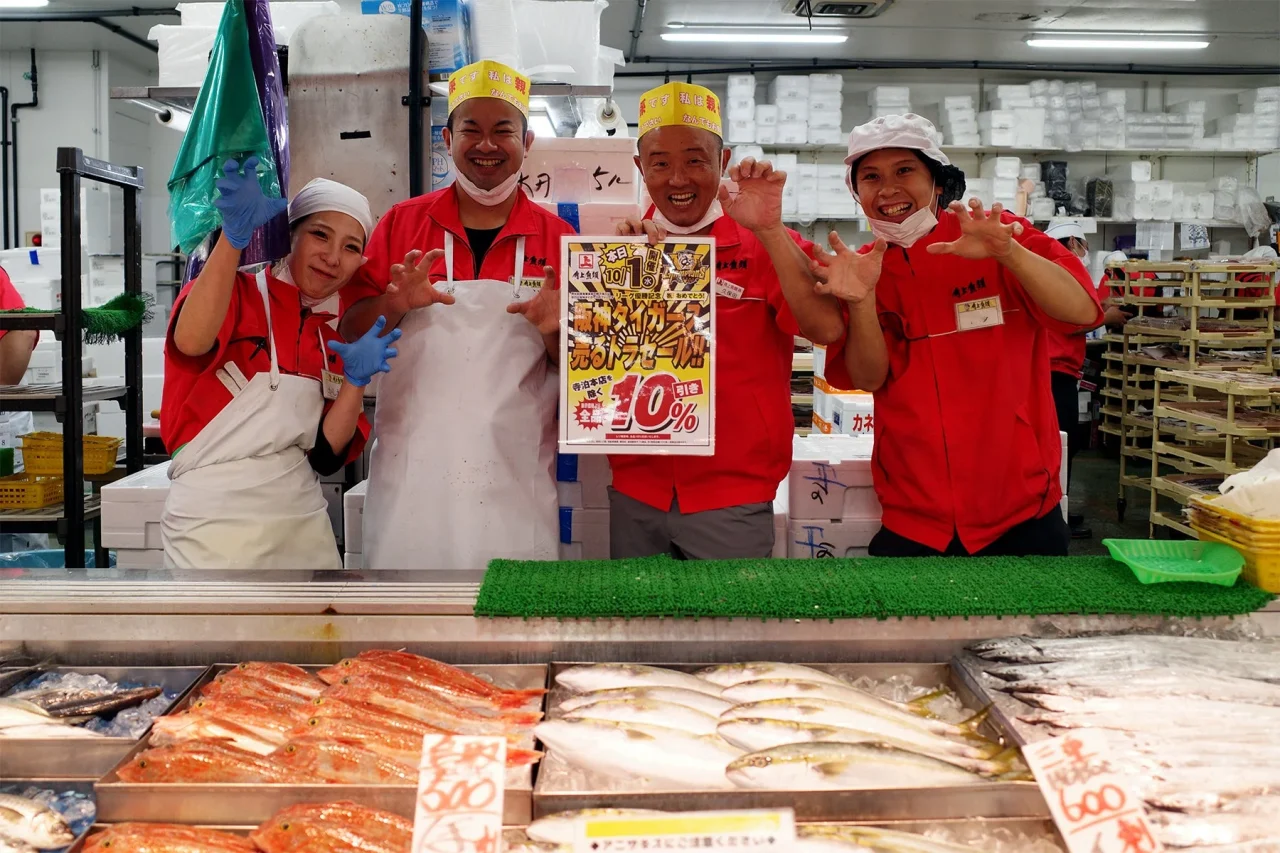 2025年開催の売る虎セールで、鮮魚売場に並ぶ赤い制服の角上魚類スタッフ