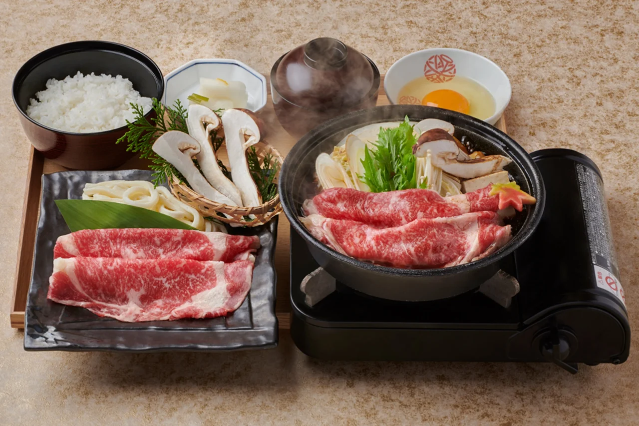 松茸と黒毛和牛のすき焼き鍋定食。鍋に牛肉と松茸、ご飯、卵が並ぶ