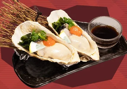 冷製牡蠣ポン酢(2個)。殻付きの牡蠣2個にレモンとオレンジ色の薬味、ポン酢